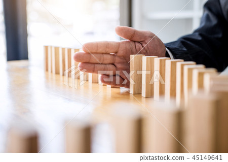 Wooden game strategy, Businessman hand stopping falling wooden d Wooden game strategy, Businessman hand stopping falling wooden d 45149641