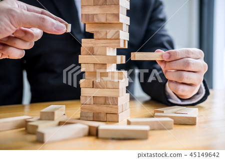 Images of hand of businesspeople placing and pulling wood block Images of hand of businesspeople placing and pulling wood block 45149642