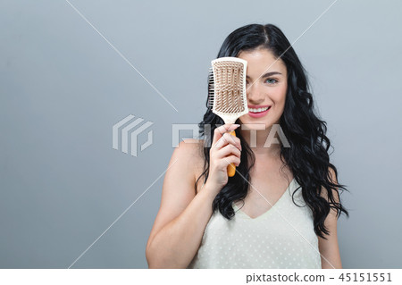 Beautiful young woman holding a hairbrush Beautiful young woman holding a hairbrush 45151551