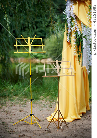 Arch for wedding ceremony in the open air, decorated with yellow fabric and flowers. Details close Arch for wedding ceremony in the open air, decorated with yellow fabric and flowers. Details close 45151995