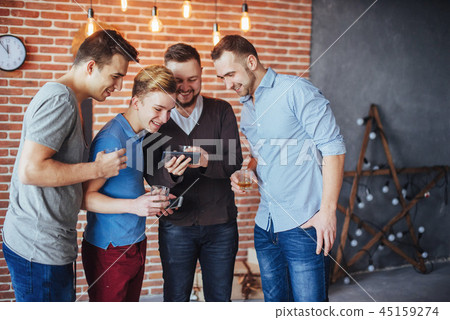 Cheerful old friends communicate with each other and phone watch,  glasses of whiskey in pub. Concep Cheerful old friends communicate with each other and phone watch,  glasses of whiskey in pub. Concep 45159274