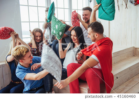 Crazy young best friends fighting pillows at home. Mixed race group of people. Concept entertainmen Crazy young best friends fighting pillows at home. Mixed race group of people. Concept entertainmen 45160460