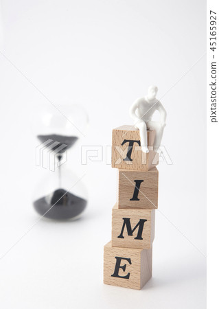 Miniature man sitting on top of a sand clock and time Miniature man sitting on top of a sand clock and time 45165927
