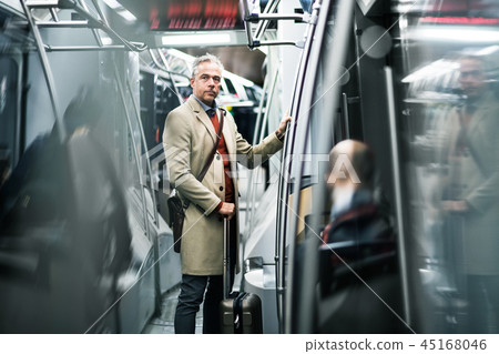 Mature businessman with suitcase travelling by subway in city. Mature businessman with suitcase travelling by subway in city. 45168046