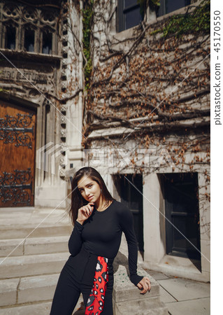 stylish brunette standing next to the entance to a building stylish brunette standing next to the entance to a building 45170550