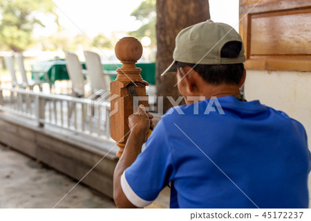 Asian man carpenter treating a wooden with chisel outdoor. 45172237