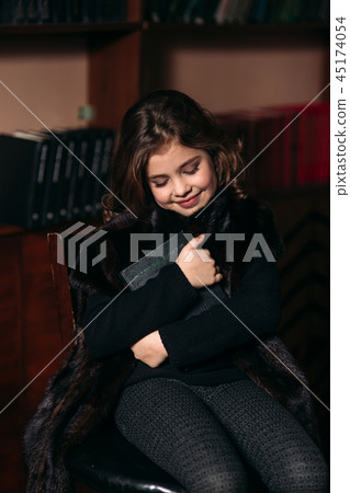 Beautiful little girl is reading a book in the library. 45174054