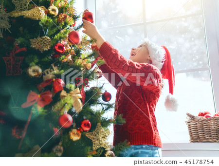 girl is decorating Christmas tree 45178754