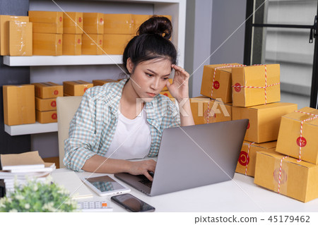stressed woman working with laptop and parcel box 45179462