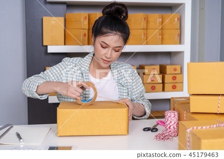 woman online entrepreneur using tape to packing woman online entrepreneur using tape to packing 45179463