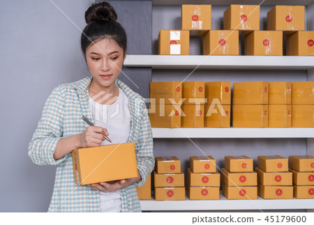 woman entrepreneur writing on parcel box woman entrepreneur writing on parcel box 45179600