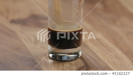Closeup espresso in glass with cold water on wood table Closeup espresso in glass with cold water on wood table 45182227