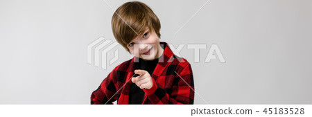 Cute confident serious little caucasian boy in checkered shirt pointing his finger on camera on grey 45183528