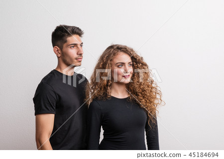 Portrait of a young couple standing in a studio, wearing black clothes. 45184694
