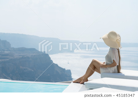 young woman enjoying a magnificent view of Santorini near the pool. young woman enjoying a magnificent view of Santorini near the pool. 45185347