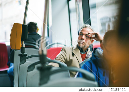 Tired mature businessman travelling by bus in city. 45185431
