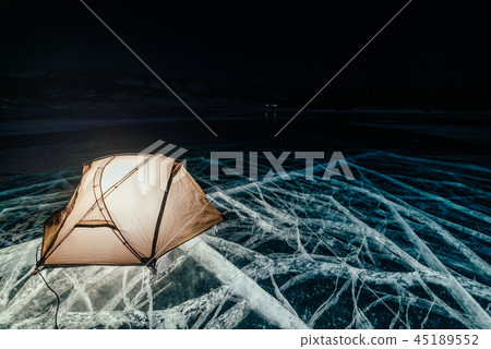 Fire on ice at night. Campground on ice. Tent stands next to bonfire. Lake Baikal. Nearby there is 45189552