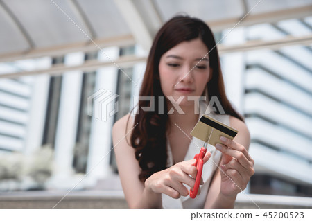 Female hands cutting credit card with scissors. 45200523