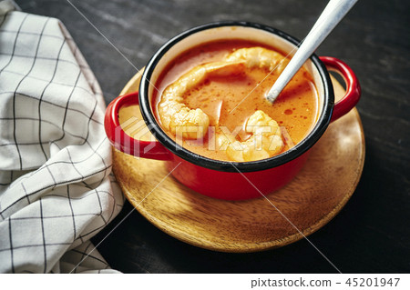 traditional Thai soup with shrimp in a red pot and a spoon traditional Thai soup with shrimp in a red pot and a spoon 45201947