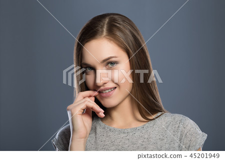 Beautiful young girl on a gray background smiling Beautiful young girl on a gray background smiling 45201949