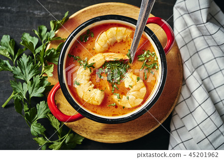 traditional Thai soup with shrimp in a red pot and a spoon with parsley traditional Thai soup with shrimp in a red pot and a spoon with parsley 45201962