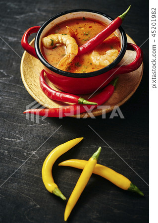 traditional Thai soup with shrimp in a red pot with chilli pepper traditional Thai soup with shrimp in a red pot with chilli pepper 45201982