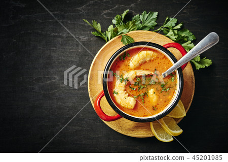 traditional Thai soup with shrimp in a red pot and a spoon with parsley traditional Thai soup with shrimp in a red pot and a spoon with parsley 45201985