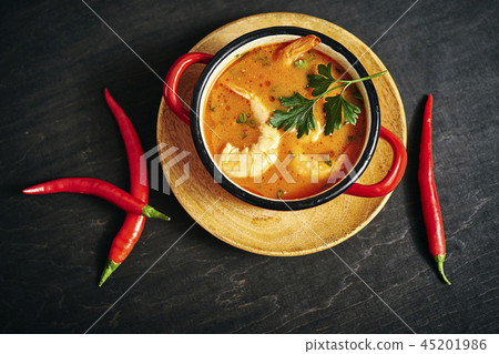 traditional Thai soup with shrimp in a red pot with parsley and chilli pepper traditional Thai soup with shrimp in a red pot with parsley and chilli pepper 45201986