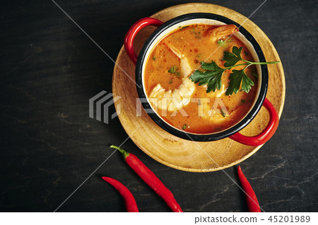 traditional Thai soup with shrimp in a red pot with parsley and chilli pepper traditional Thai soup with shrimp in a red pot with parsley and chilli pepper 45201989