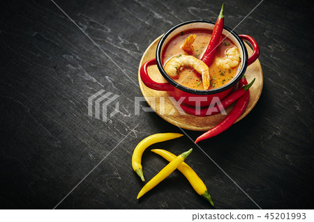 traditional Thai soup with shrimp in a red pot with chilli pepper traditional Thai soup with shrimp in a red pot with chilli pepper 45201993