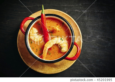 traditional Thai soup with shrimp in a red pot with chilli pepper traditional Thai soup with shrimp in a red pot with chilli pepper 45201995