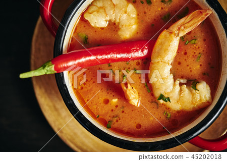traditional Thai soup with shrimp in a red pot with chilli pepper traditional Thai soup with shrimp in a red pot with chilli pepper 45202018