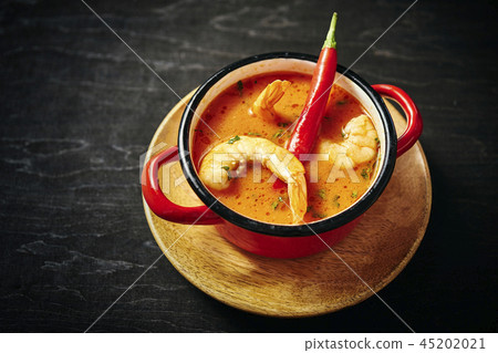 traditional Thai soup with shrimp in a red pot with chilli pepper 45202021