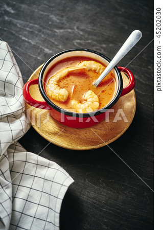 traditional Thai soup with shrimp in a red pot and a spoon traditional Thai soup with shrimp in a red pot and a spoon 45202030