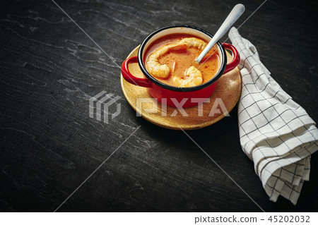 traditional Thai soup with shrimp in a red pot and a spoon traditional Thai soup with shrimp in a red pot and a spoon 45202032
