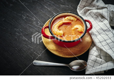 traditional Thai soup with shrimp in a red pot and a spoon traditional Thai soup with shrimp in a red pot and a spoon 45202033