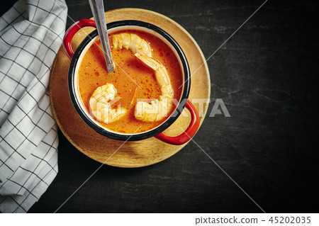 traditional Thai soup with shrimp in a red pot and a spoon traditional Thai soup with shrimp in a red pot and a spoon 45202035