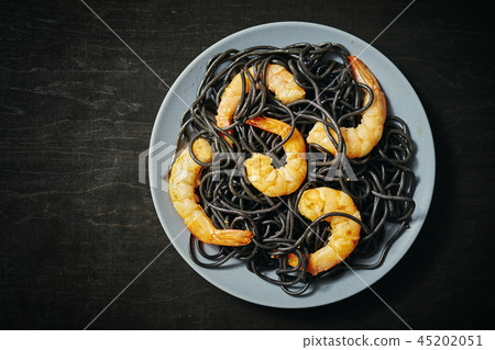 fresh, delicious black spaghetti with grilled shrimps on a gray plate on a black table fresh, delicious black spaghetti with grilled shrimps on a gray plate on a black table 45202051