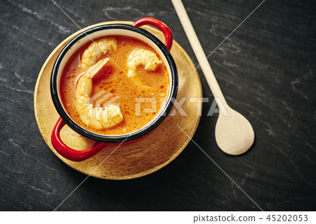 traditional Thai soup with shrimp in a red pot and a wooden spoon traditional Thai soup with shrimp in a red pot and a wooden spoon 45202053