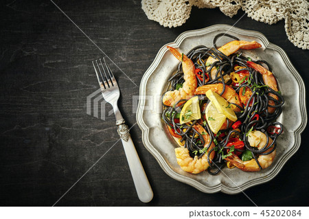 fresh, delicious black spaghetti with grilled prawns, tomatoes, chilli on an old silver plate fresh, delicious black spaghetti with grilled prawns, tomatoes, chilli on an old silver plate 45202084