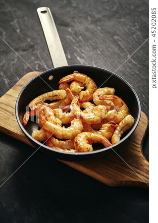 fresh delicious fried prawns in a pan and wooden board fresh delicious fried prawns in a pan and wooden board 45202085