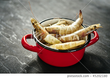 fresh delicious raw tiger prawns in a red pot on a black table fresh delicious raw tiger prawns in a red pot on a black table 45202180
