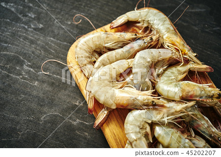 fresh delicious raw tiger prawns on a wooden board on a black table fresh delicious raw tiger prawns on a wooden board on a black table 45202207