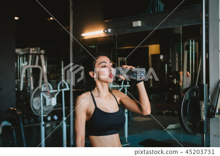 Asian young woman drinking water in the gym. Asian young woman drinking water in the gym. 45203731