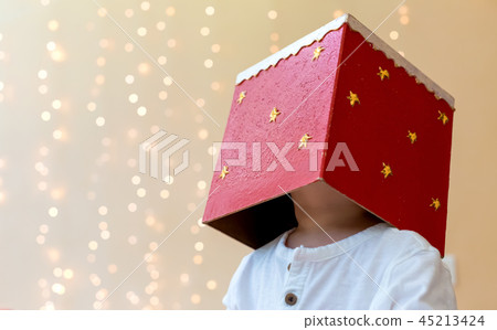 Toddler boy playing with a Christmas gift on his head Toddler boy playing with a Christmas gift on his head 45213424