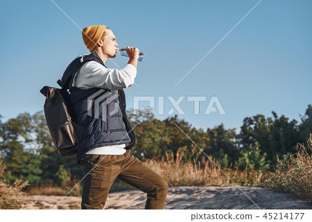 Young stylish tourist blogger is drinking water while walking at the mountains 45214177