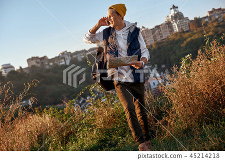 Young tourist blogger is exploring the map and talking on the smart phone Young tourist blogger is exploring the map and talking on the smart phone 45214218
