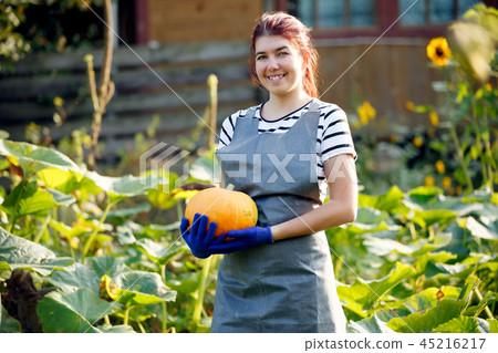 Image of smiling woman with pumpkin in hands at garden Image of smiling woman with pumpkin in hands at garden 45216217