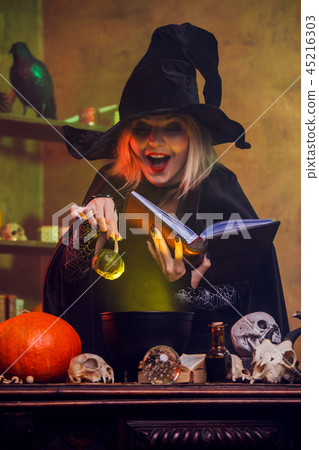 Image of witch reading spell pumpkin in hand 45216303