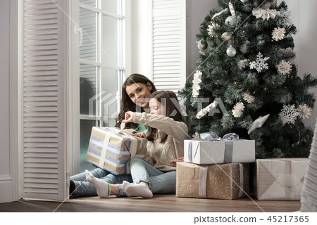 Mother and daughter unwrapping gift Mother and daughter unwrapping gift 45217365
